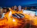 Widok z lotu ptaka na nocne miasto z długimi smugami świateł samochodowych i tramwajowych.