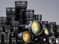 Duża kolekcja obiektywów fotograficznych Nikon ułożonych w stosy.