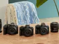 Trzy czarne aparaty Canon EOS z obiektywami i dodatkowe obiektywy na drewnianym stole.